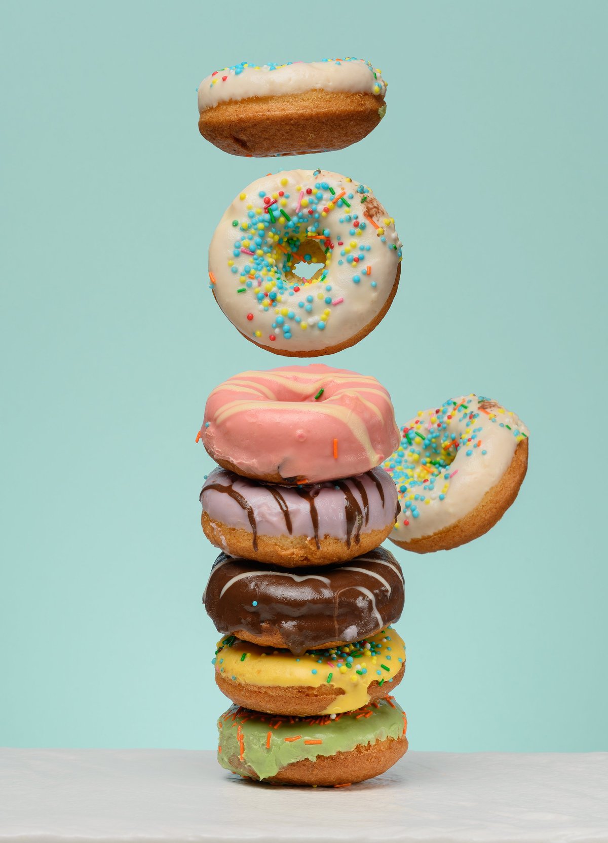 Stack of donuts with various fillings and glazes on a blue background